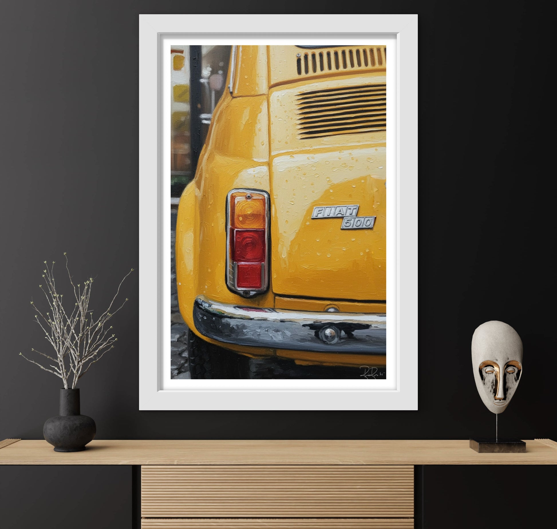 Framed picture of a yellow car on a dark wall with decorative items below.