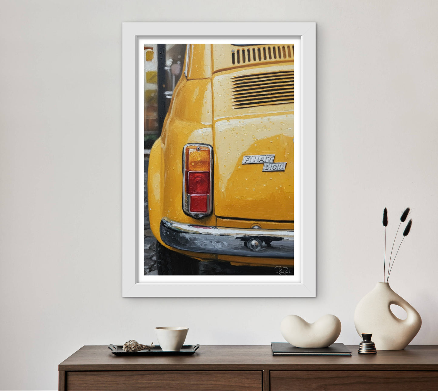 Framed photograph of a yellow car on a wall above a wooden console table with decorative items.