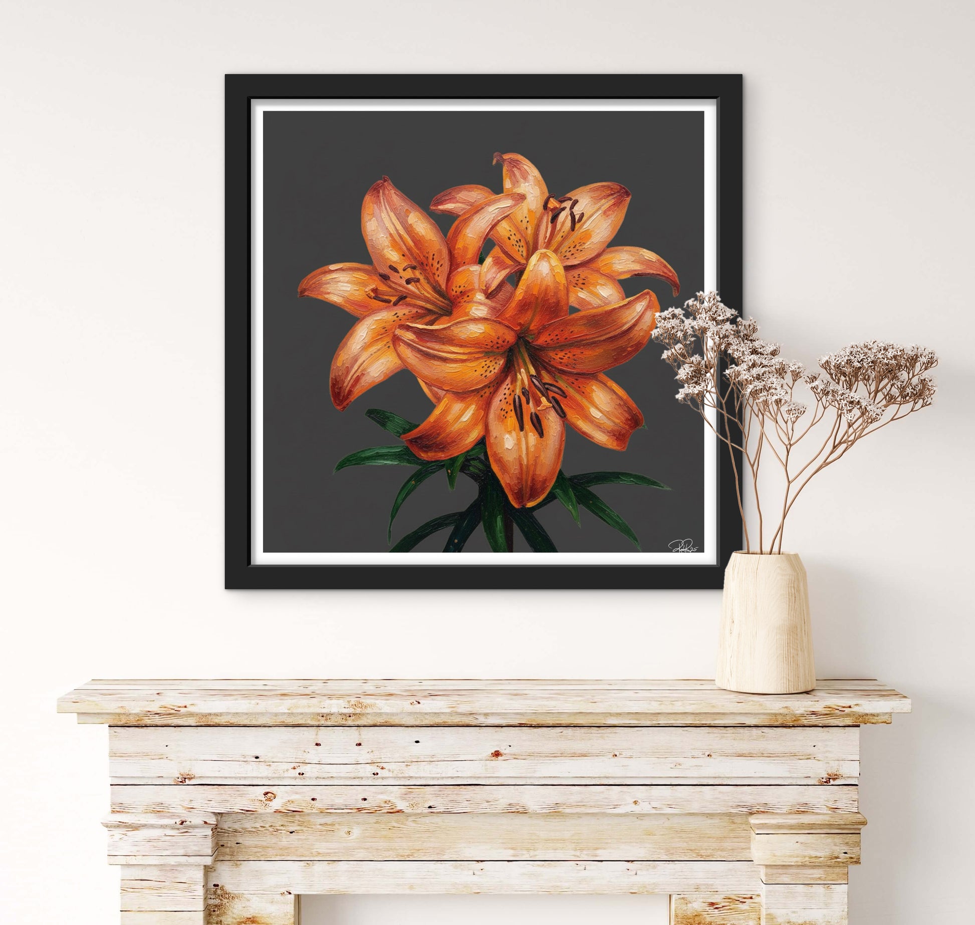 Framed artwork of orange lilies on a wall above a wooden console table.