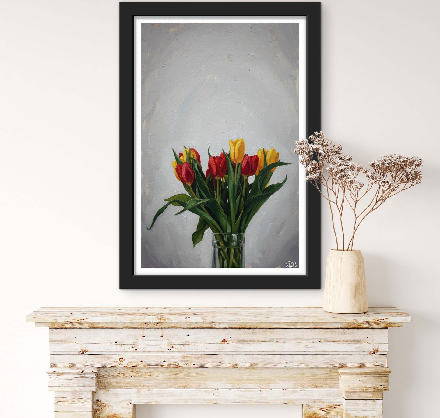 Framed artwork of tulips on a wooden console table with a vase of dried flowers.