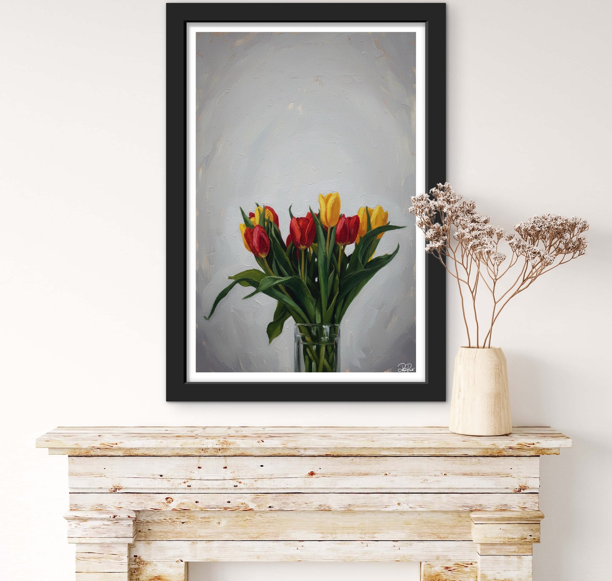 Framed artwork of tulips on a wooden console table with a vase of dried flowers.