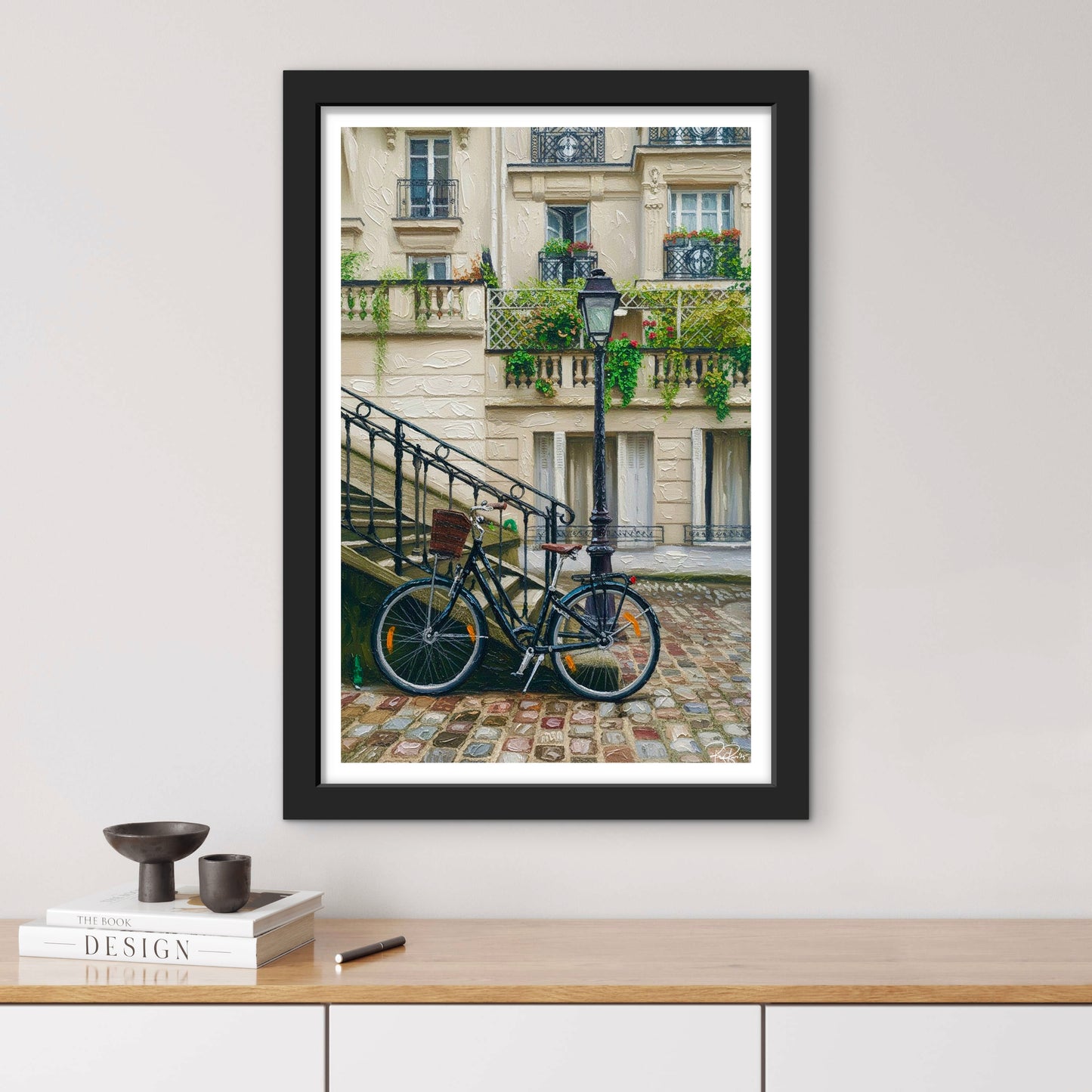 Framed photograph of a bicycle on a Parisian street with a building in the background.