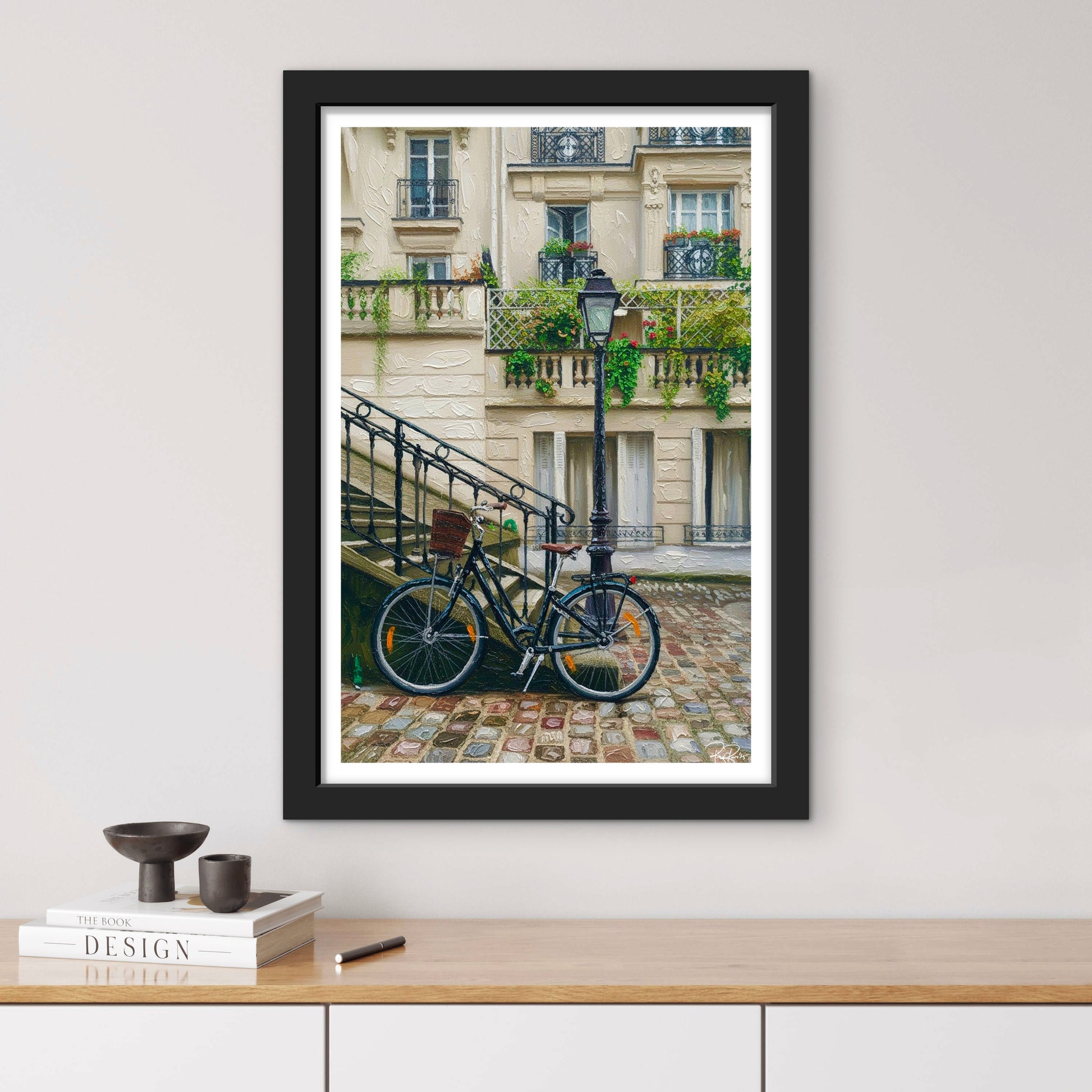 Framed photograph of a bicycle on a Parisian street with a building in the background.