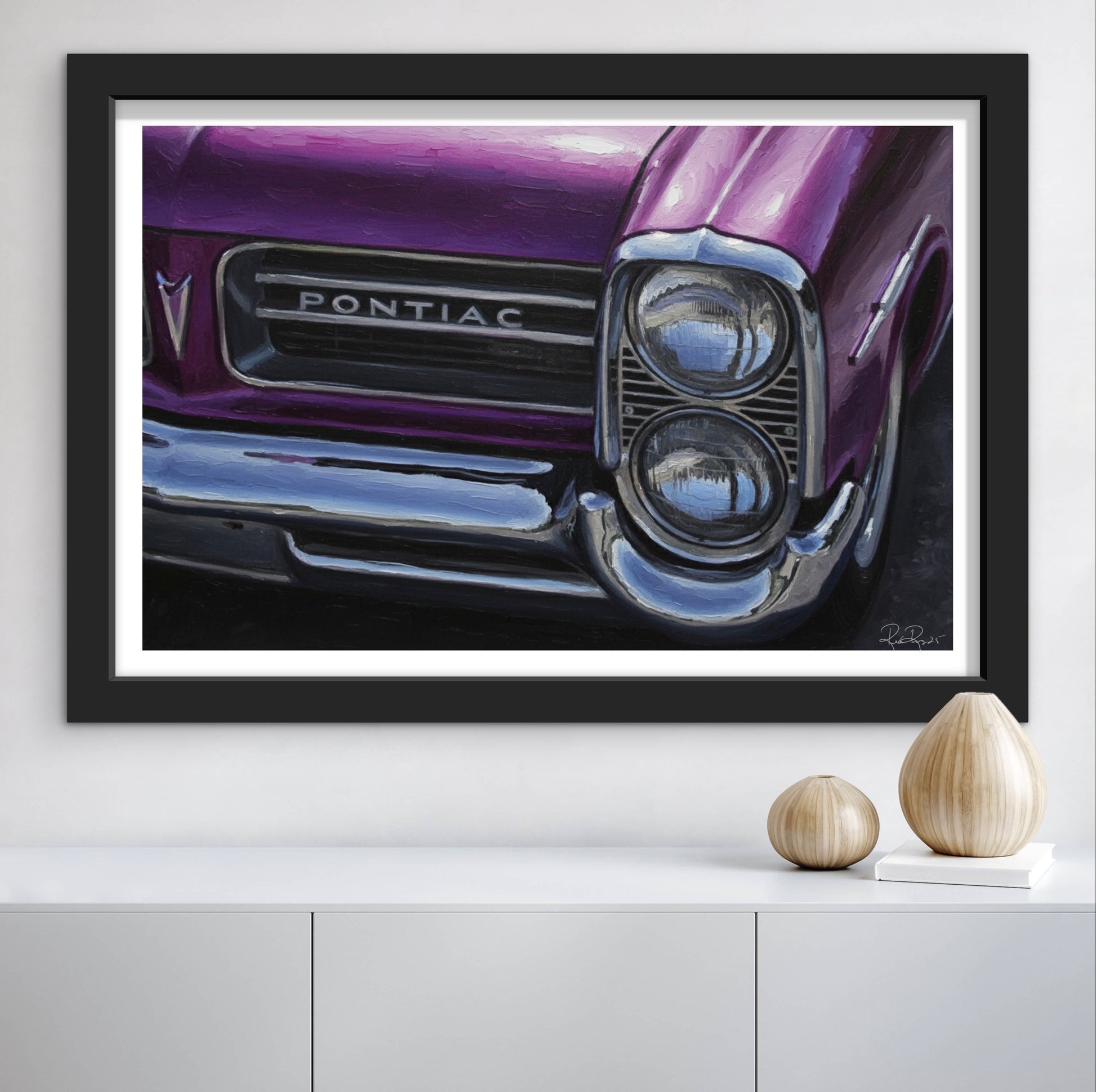 Framed artwork of a purple Pontiac car on a white wall.