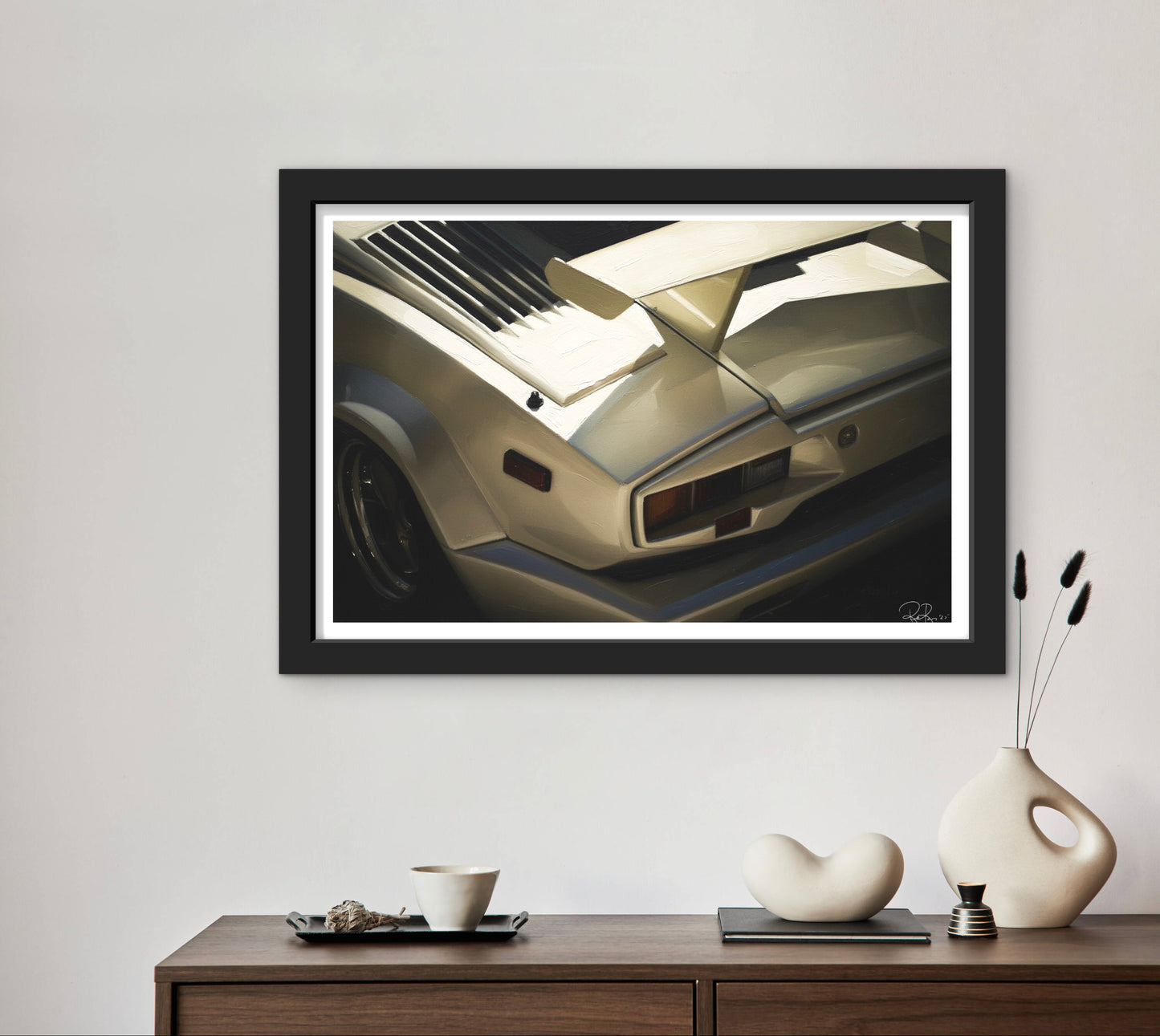 Framed artwork of a car on a wall above a wooden console table with decorative items.