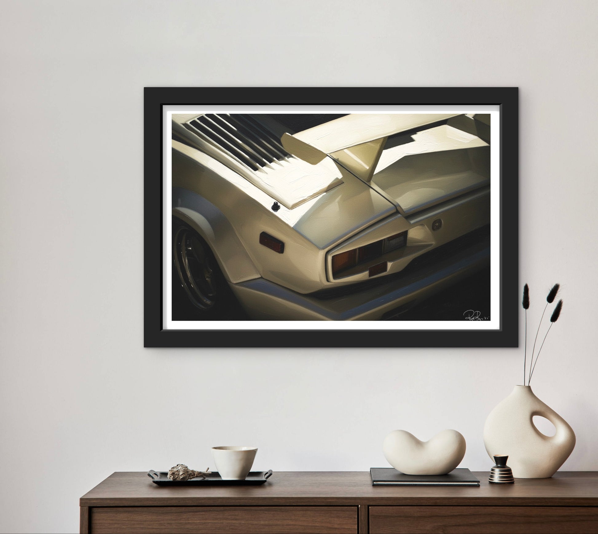 Framed artwork of a car on a wall above a wooden console table with decorative items.