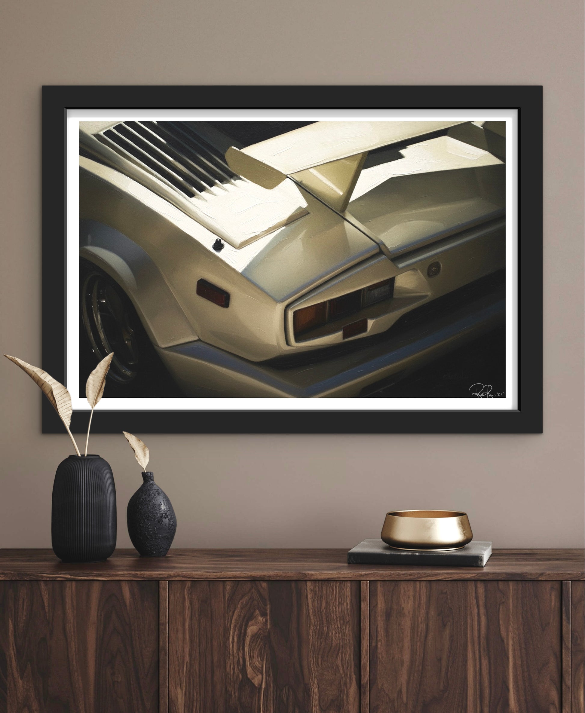 Framed artwork of a car on a wall above a wooden console table with decorative items.