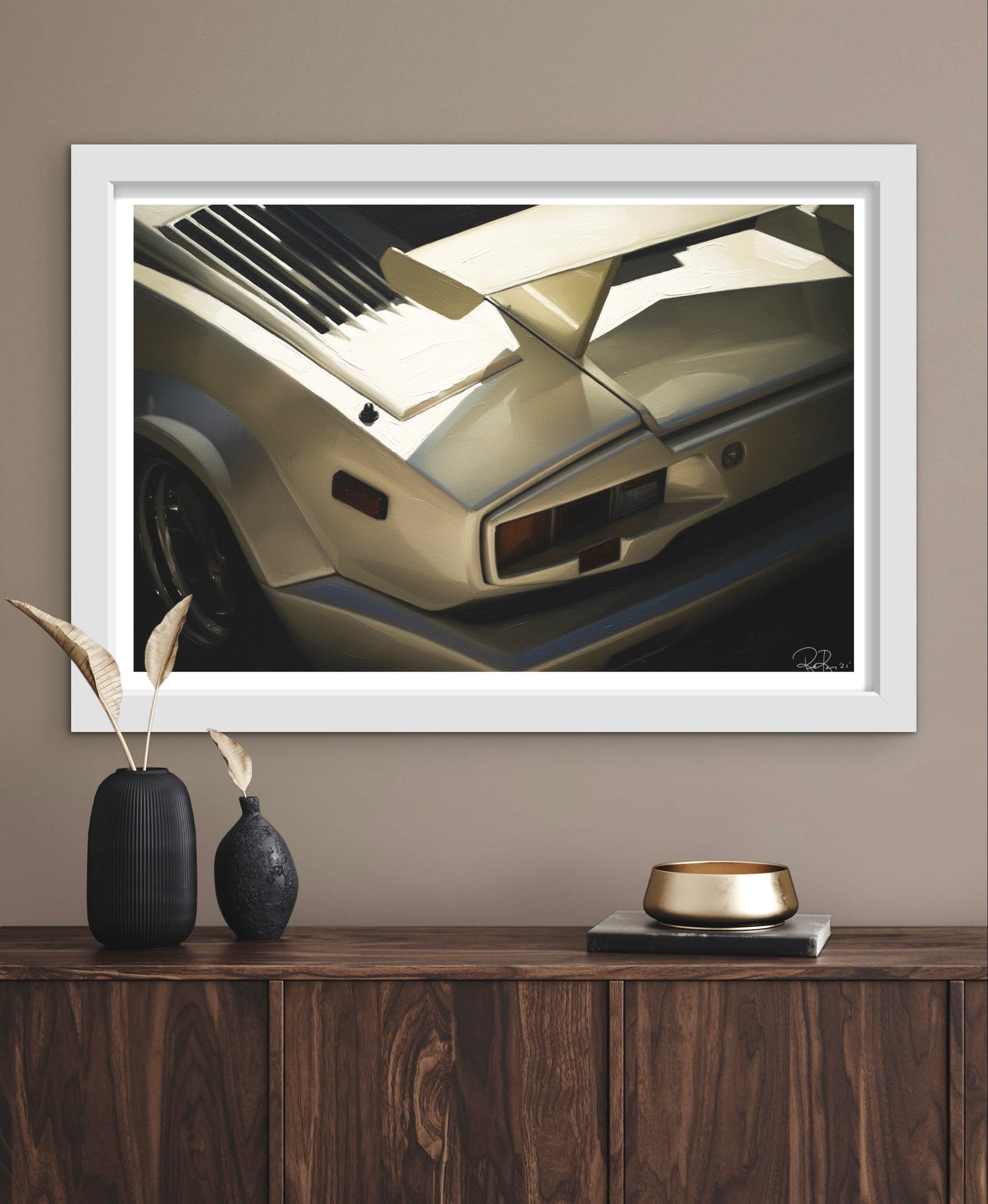 Framed artwork of a car on a wall above a wooden console table with decorative items.