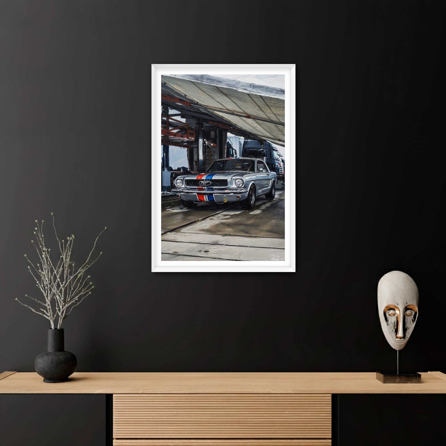 Framed artwork of a classic car on a black wall above a wooden shelf with decorative items.