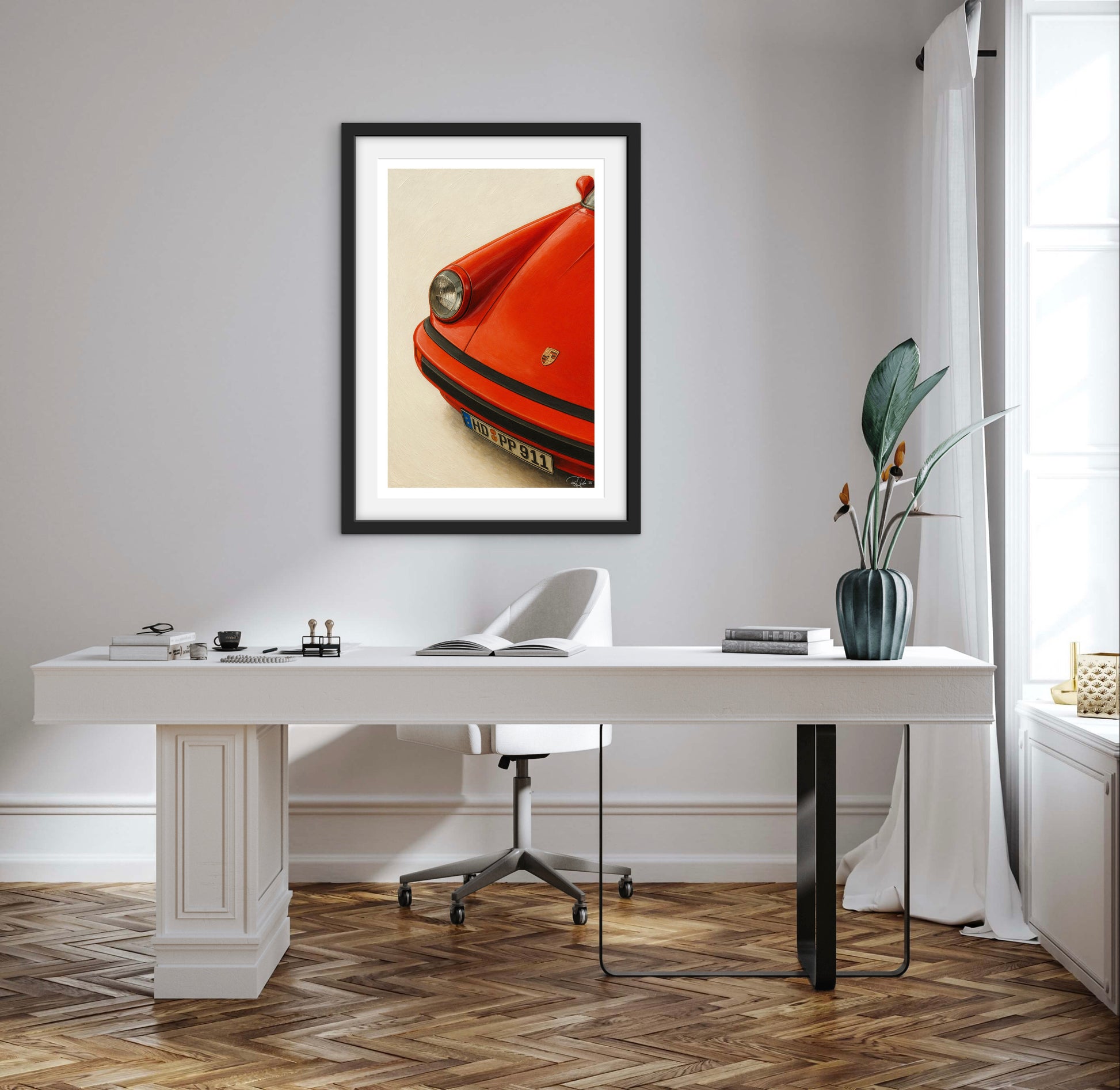 Modern office setup with a white desk, framed artwork of a red car, and decorative elements.