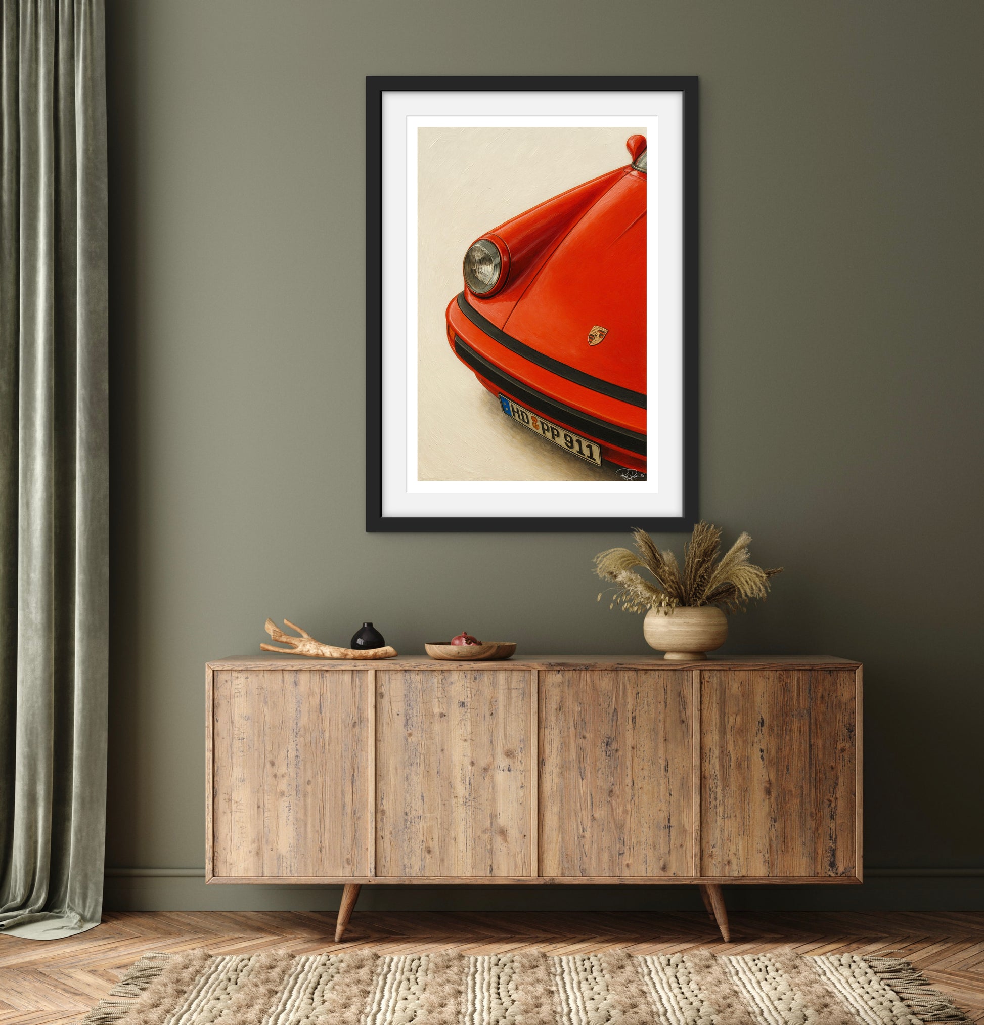 Framed artwork of a red car on a wall above a wooden sideboard.