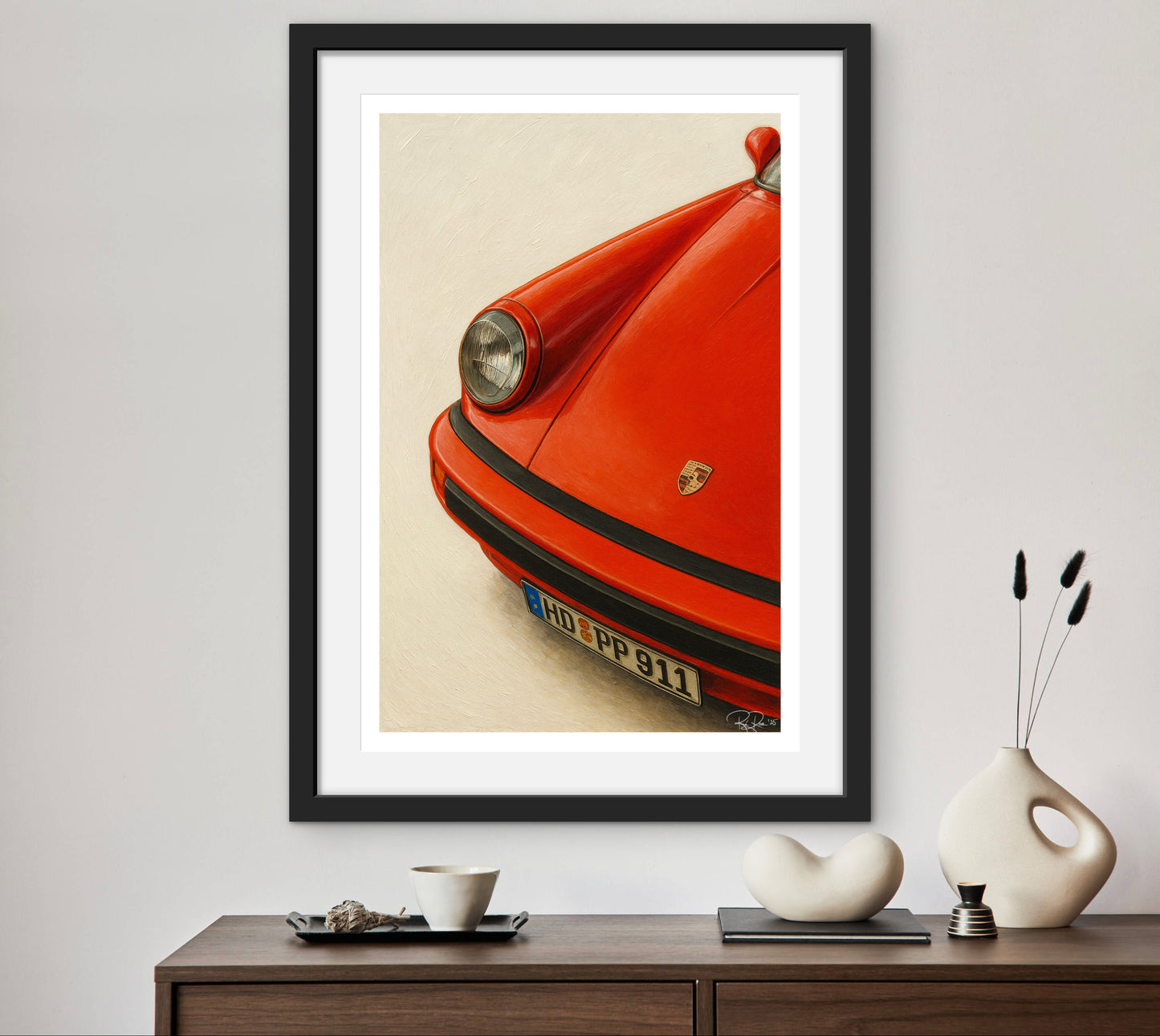 Framed artwork of a red car on a wall above a wooden console table with decorative items.