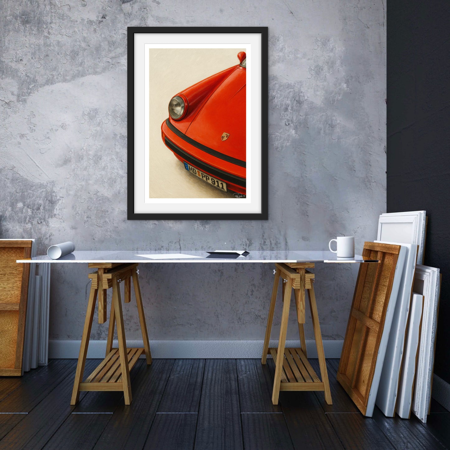 Framed artwork of a red car on a gray wall above a table.