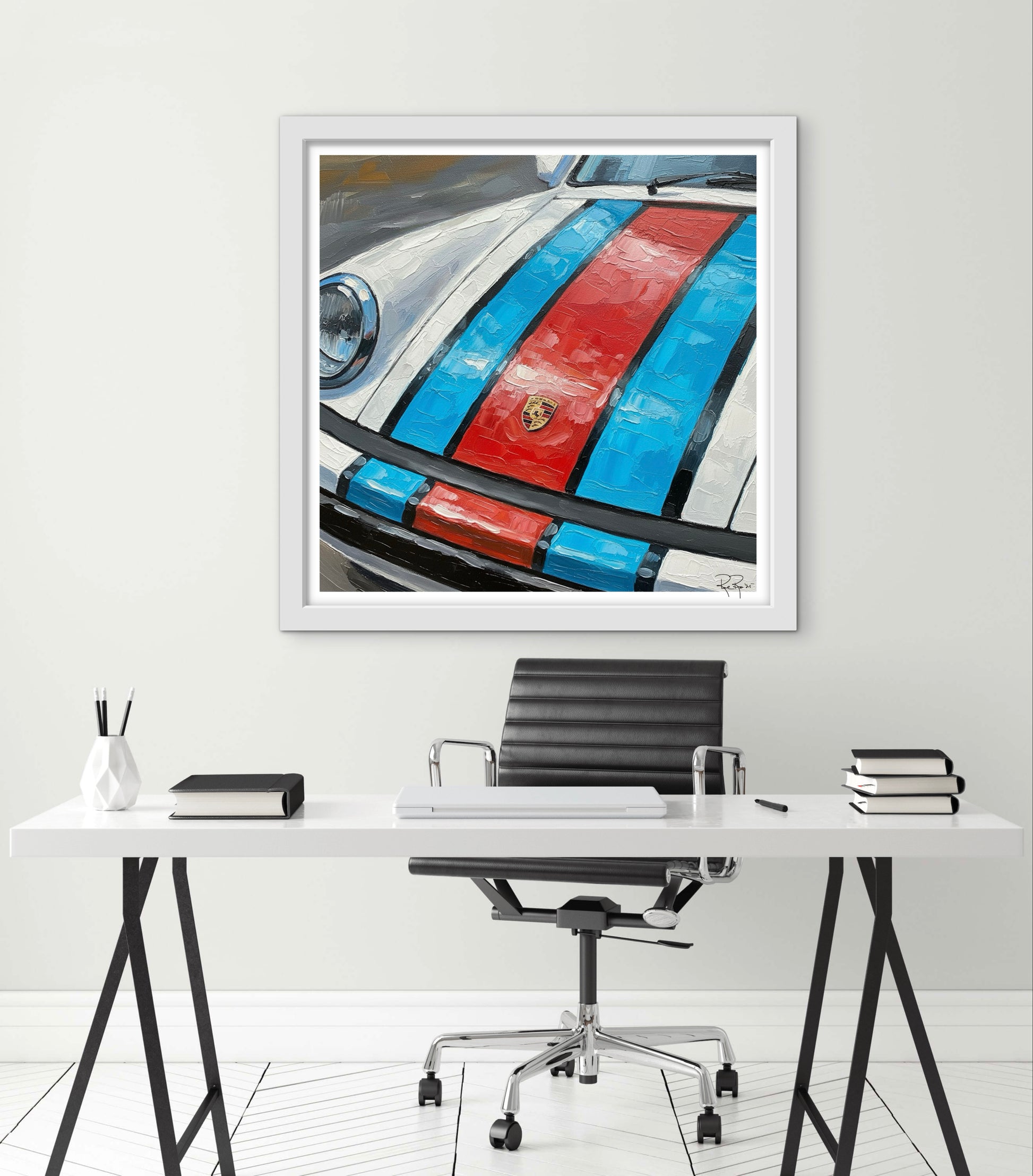 Framed artwork of a car with red and blue stripes on a white wall above a desk.