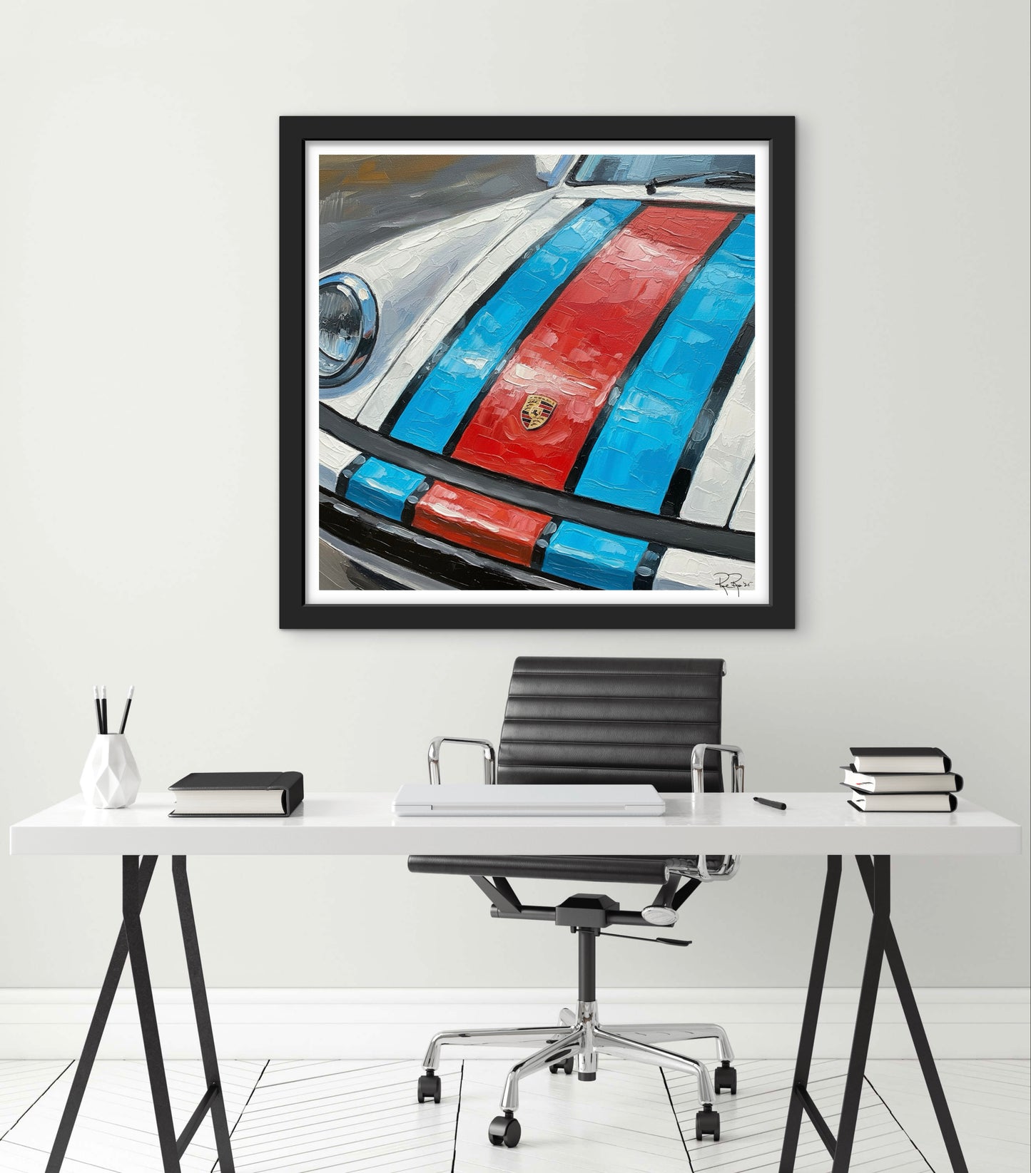Framed artwork of a car with red and blue stripes on a white wall above a desk.