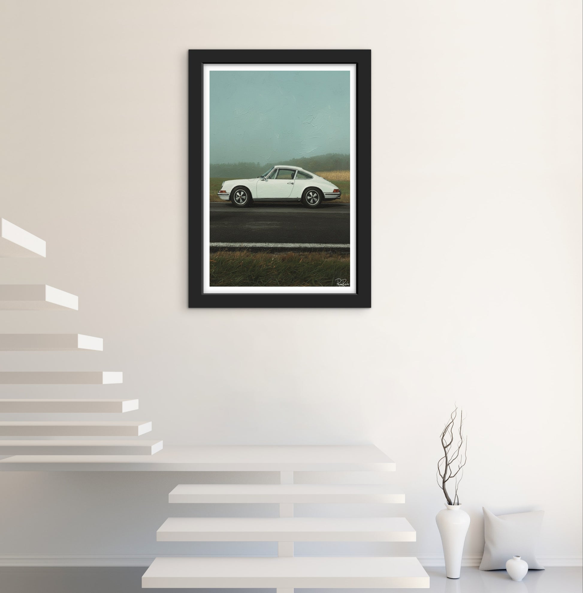 Framed artwork of a white car on a road with a scenic background, displayed in a modern interior setting.