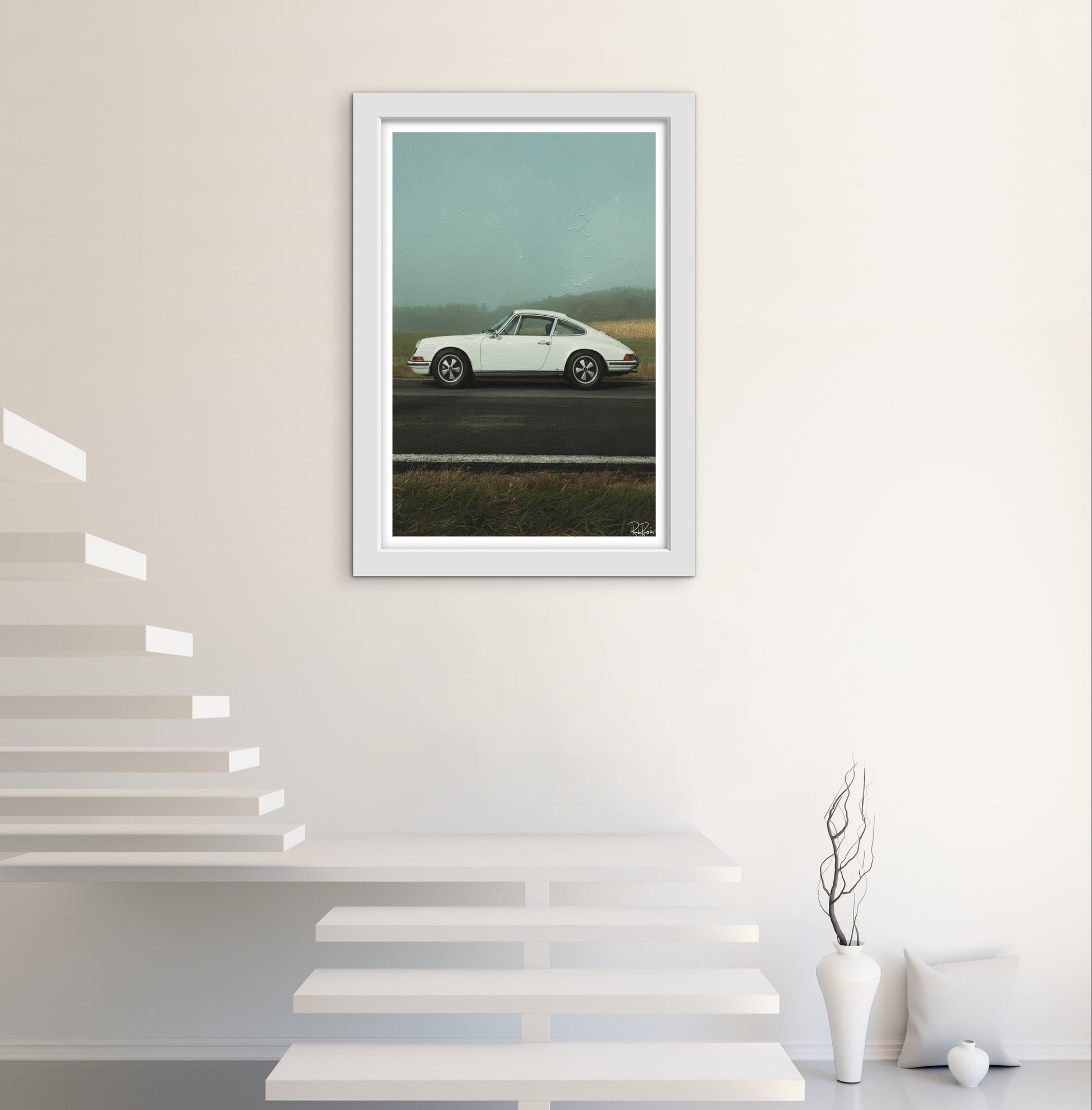 Framed artwork of a white car on a road with mountains, displayed in a modern interior setting.