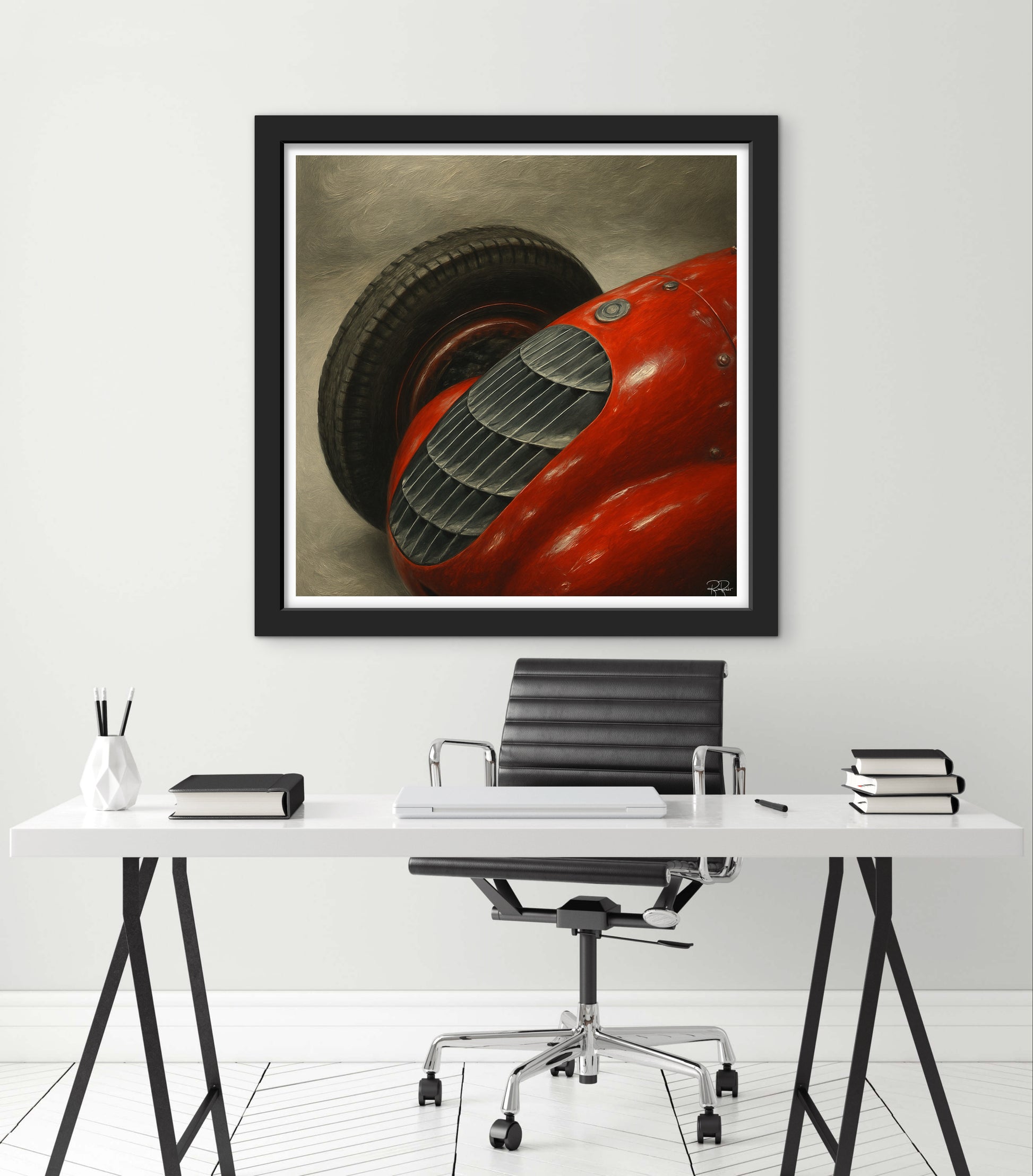 Framed artwork of a red car on a white wall above a desk.