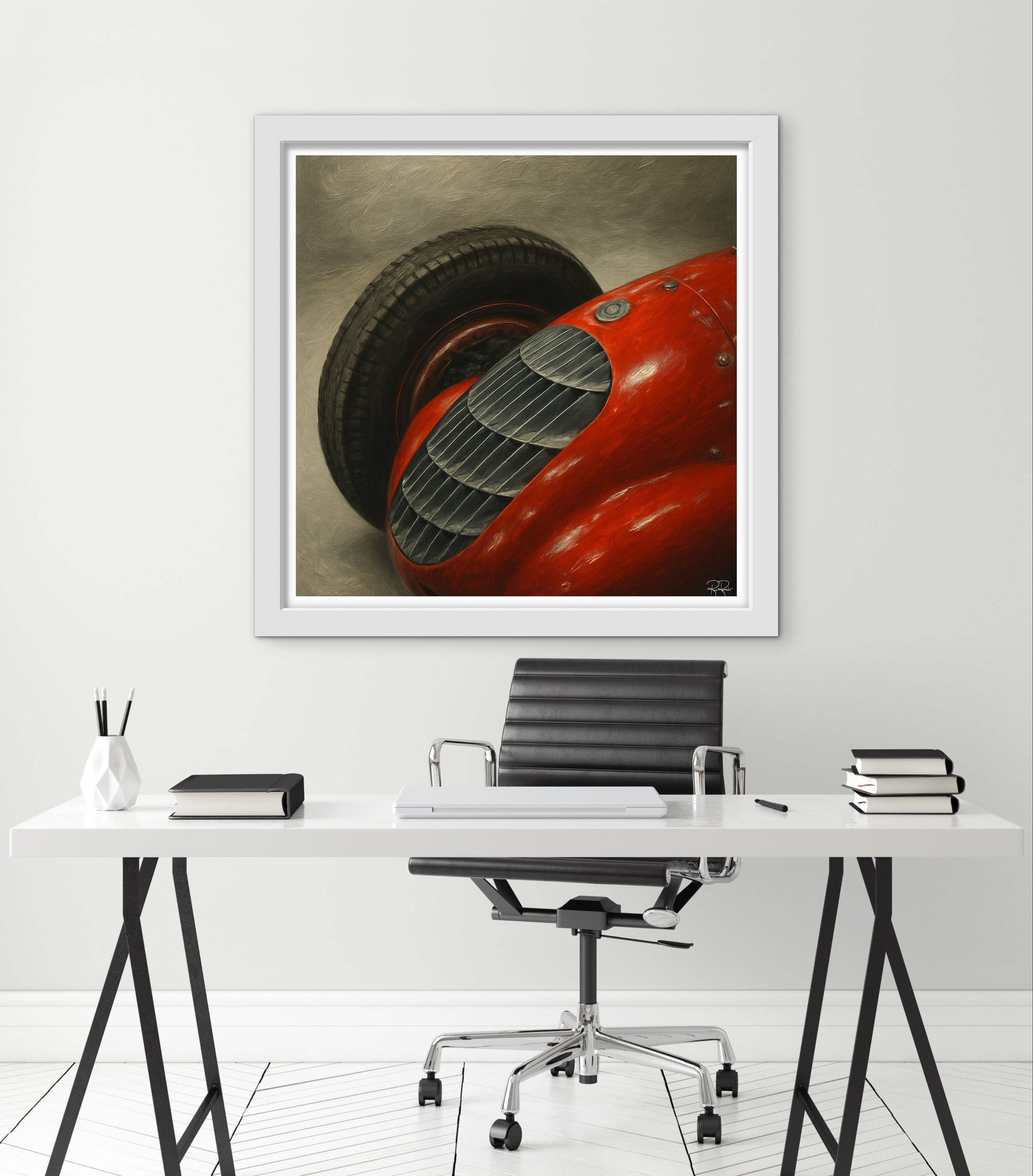 Framed artwork of a red car on a white wall above a desk.