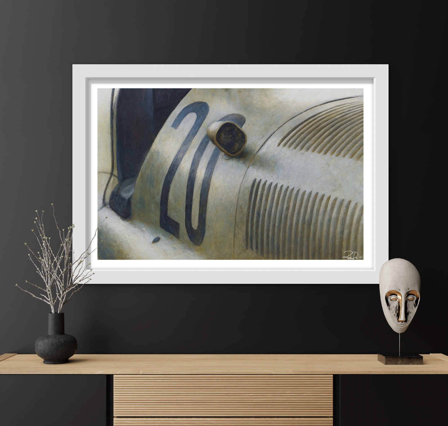 Framed artwork of a vintage car on a dark wall with decorative items below.