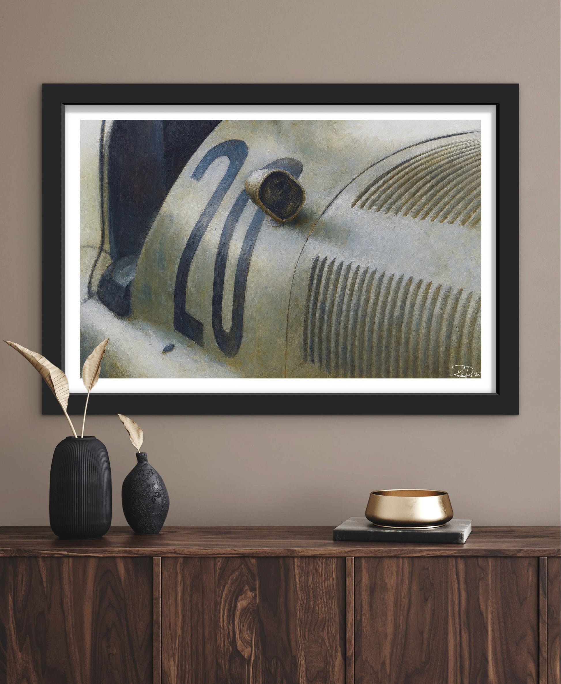 Framed artwork of a vintage car on a wall above a wooden console table.