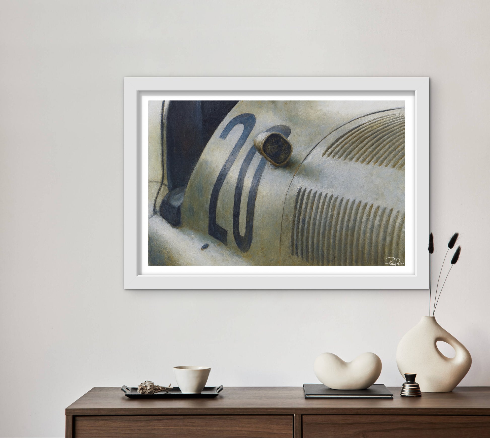 Framed artwork of a vintage car on a wall above a wooden console table with decorative items.