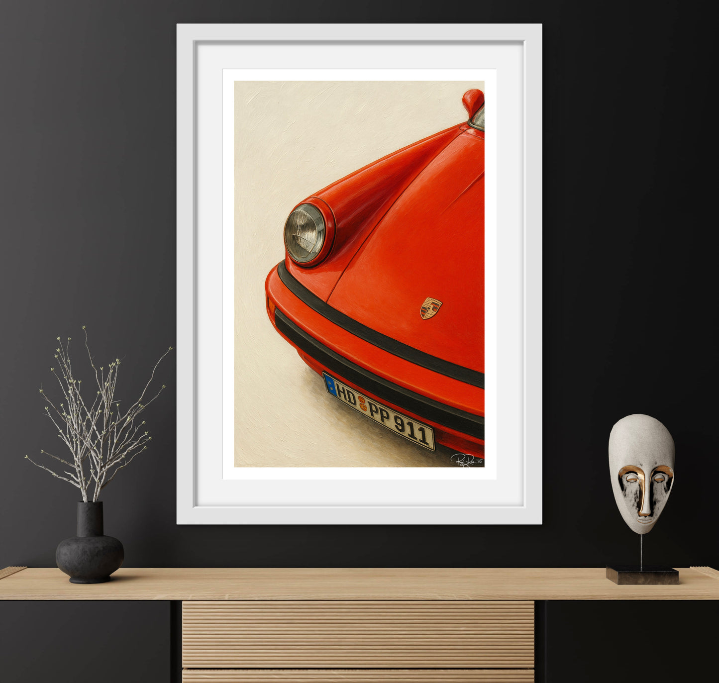 Framed artwork of a red Porsche on a wall with decorative items below.