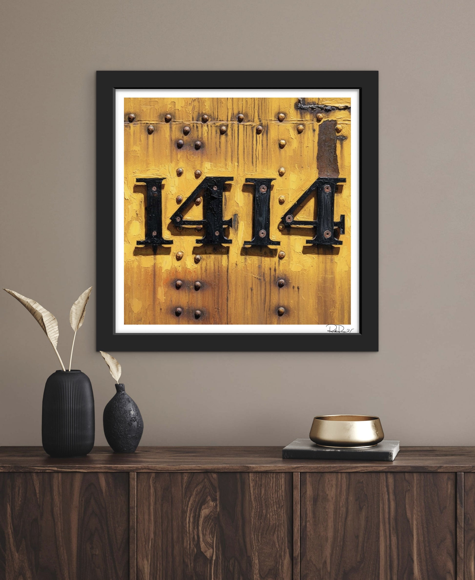 Framed artwork with the number '1414' on a wooden background, displayed on a wall above a wooden console table.