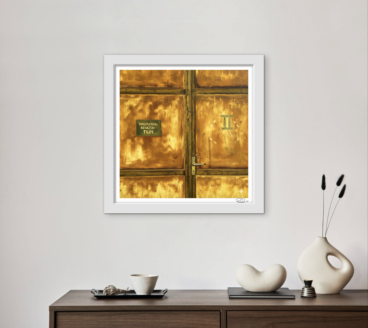 Framed artwork of a gold door on a wall above a wooden console table with decorative items.