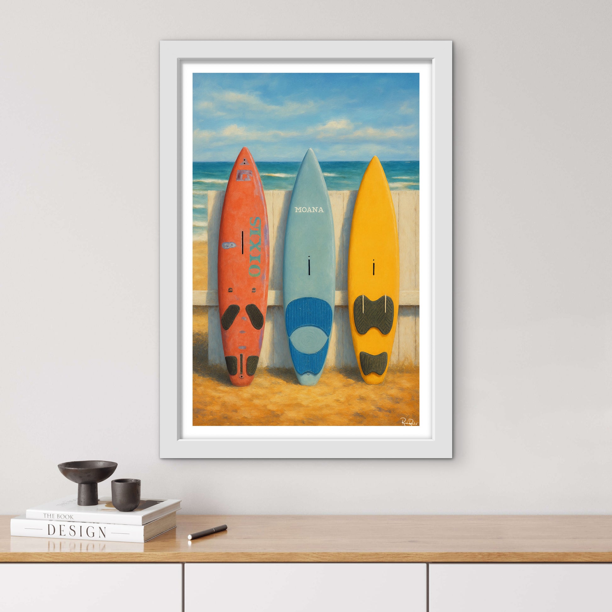 Framed artwork of three surfboards on a beach with a white frame.