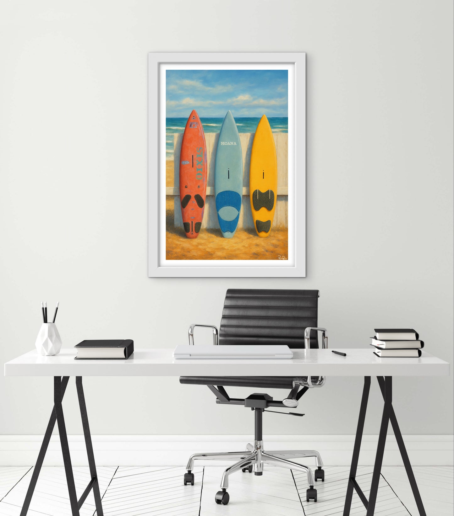 Framed artwork of surfboards on a beach above a desk with office supplies.