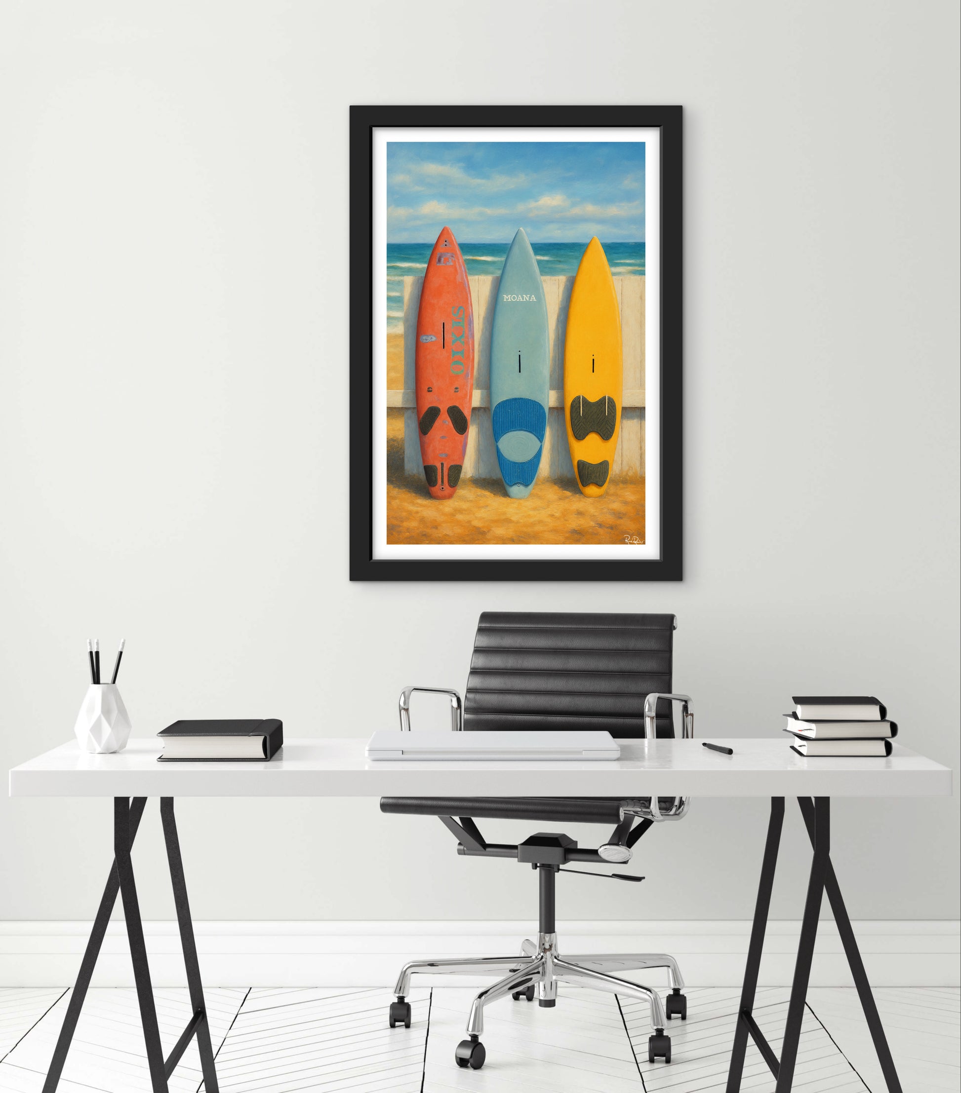 Framed artwork of surfboards on a beach with a desk and chair in the foreground.