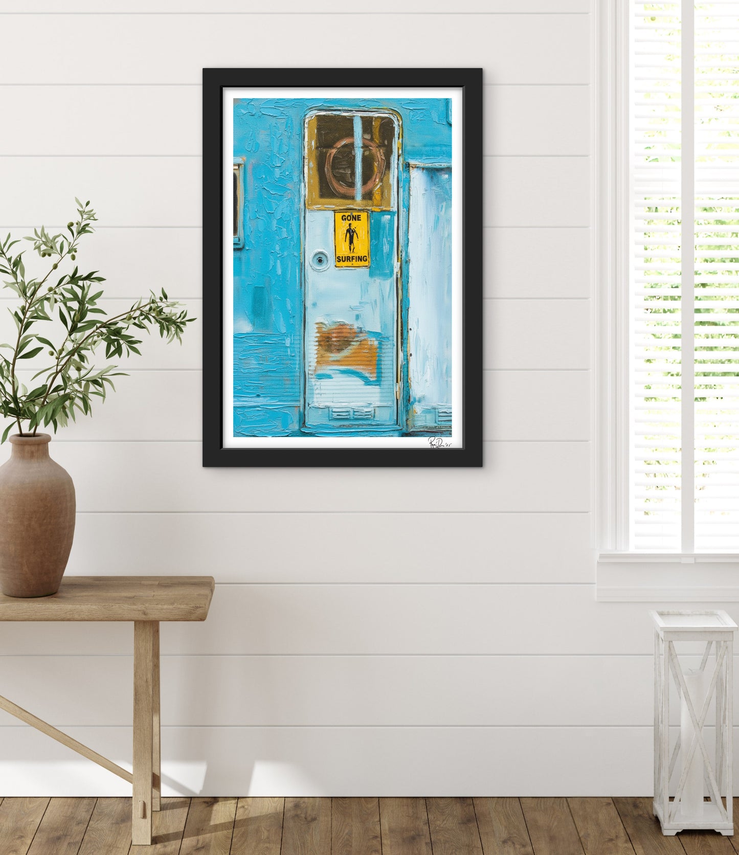 Framed artwork of a blue door with a yellow sign on a white wall.