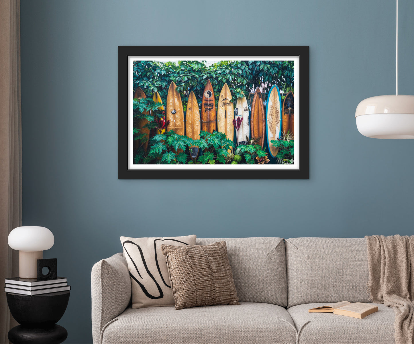 Framed artwork of surfboards in a forest on a blue wall above a sofa.