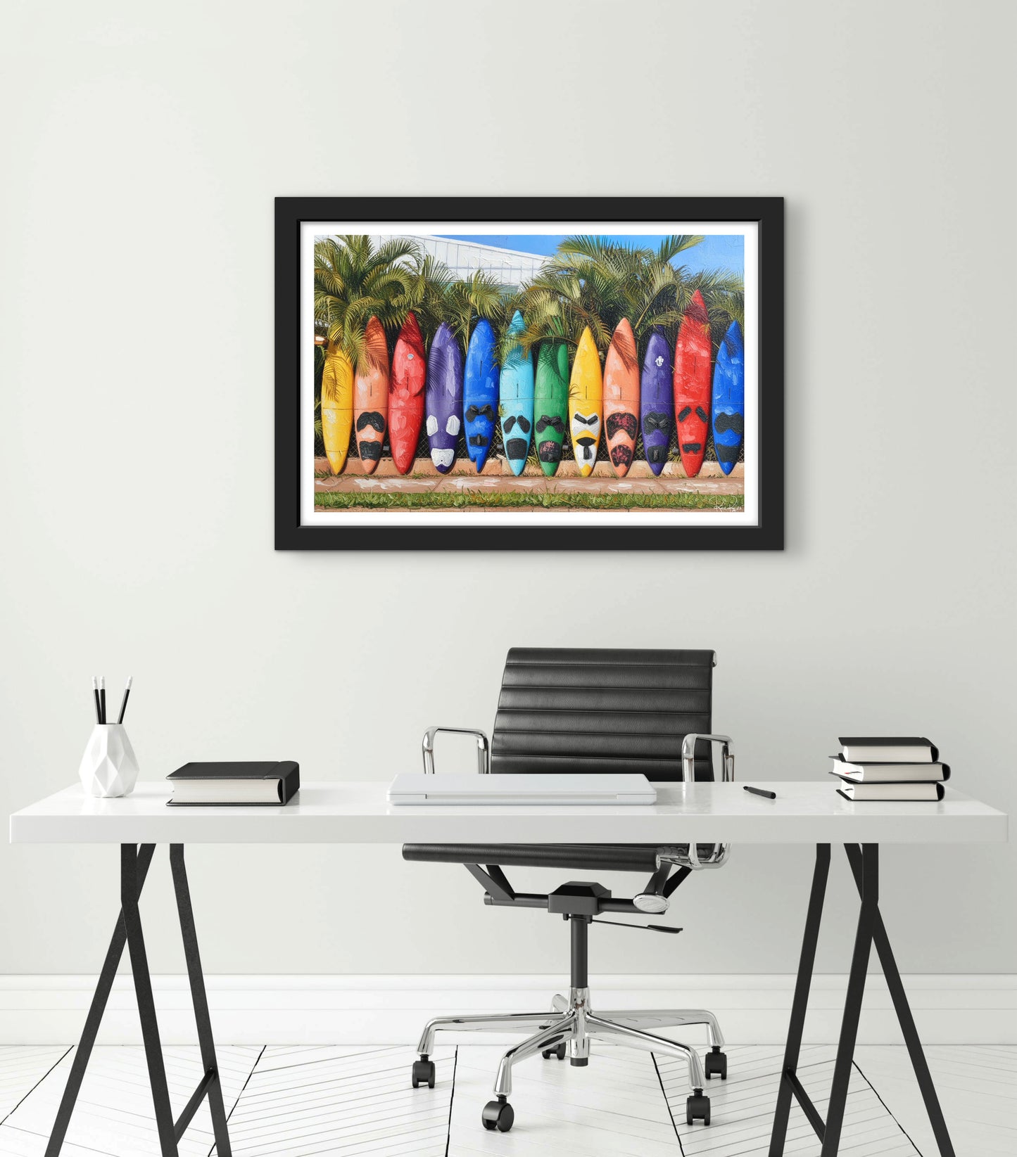 Framed artwork of colorful surfboards on a wall above a desk.