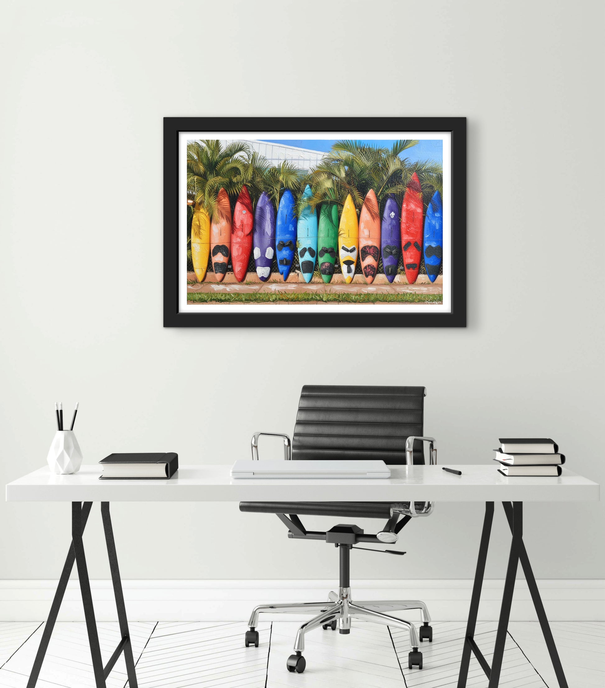 Framed artwork of colorful surfboards on a wall above a desk.