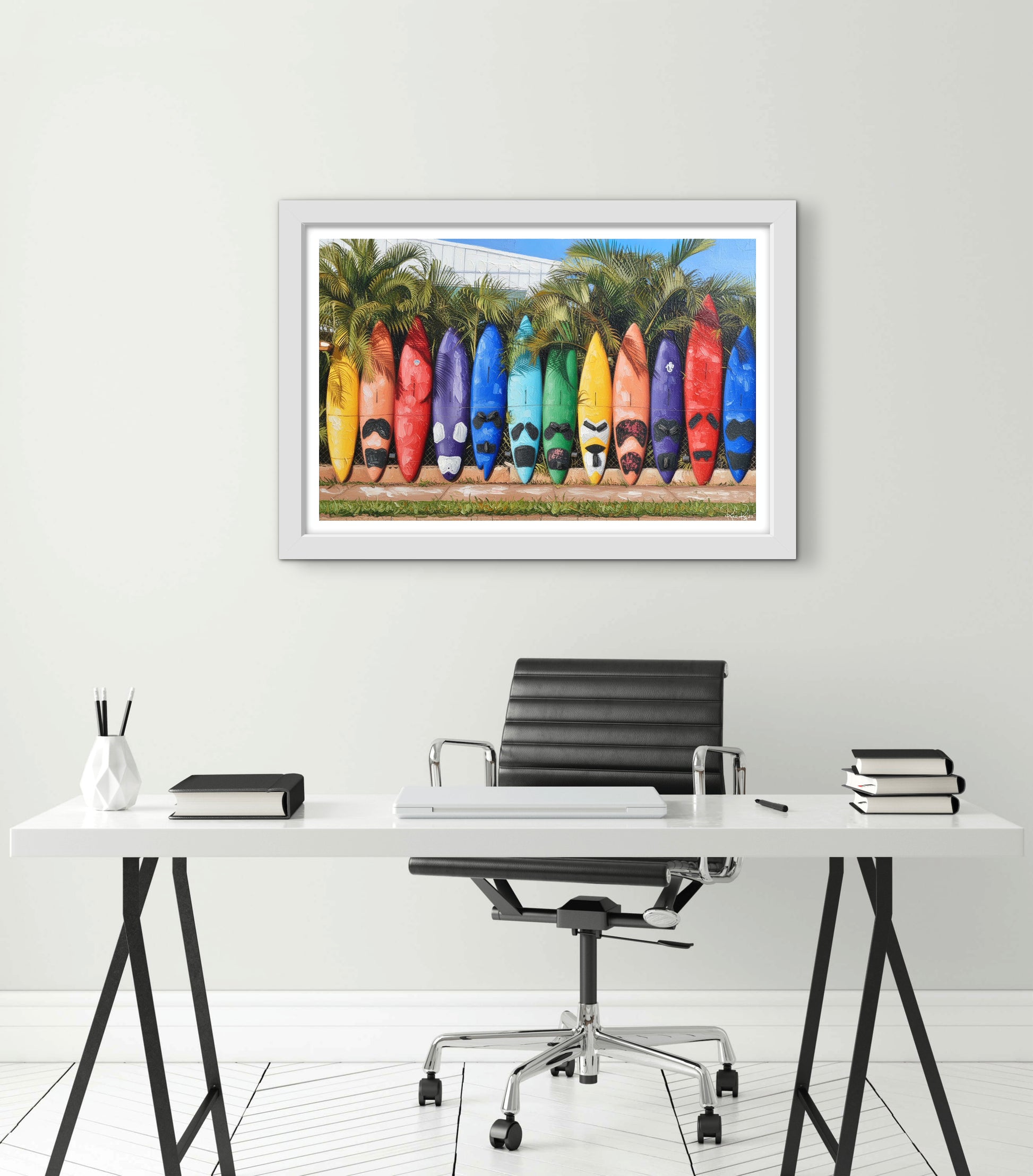 Framed artwork of colorful surfboards on a wall above a desk.