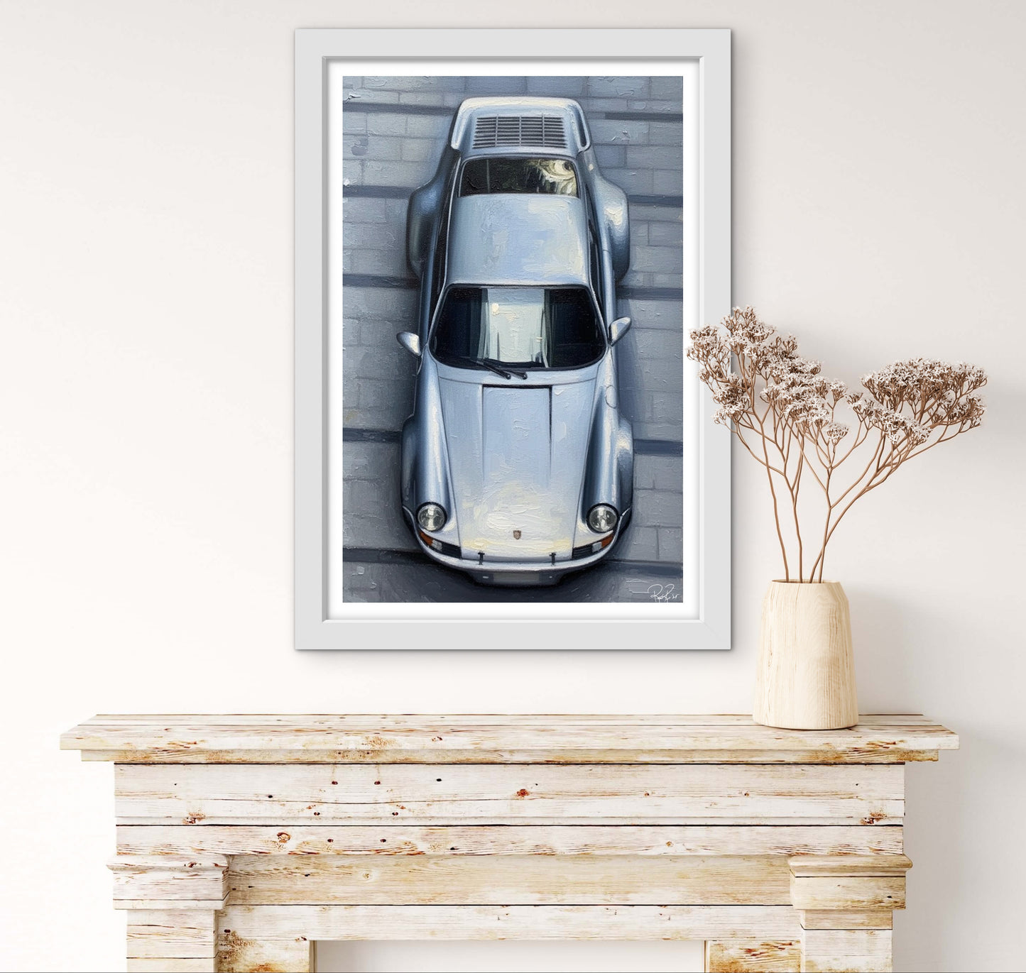 Framed artwork of a vintage car on a wall above a wooden console table.
