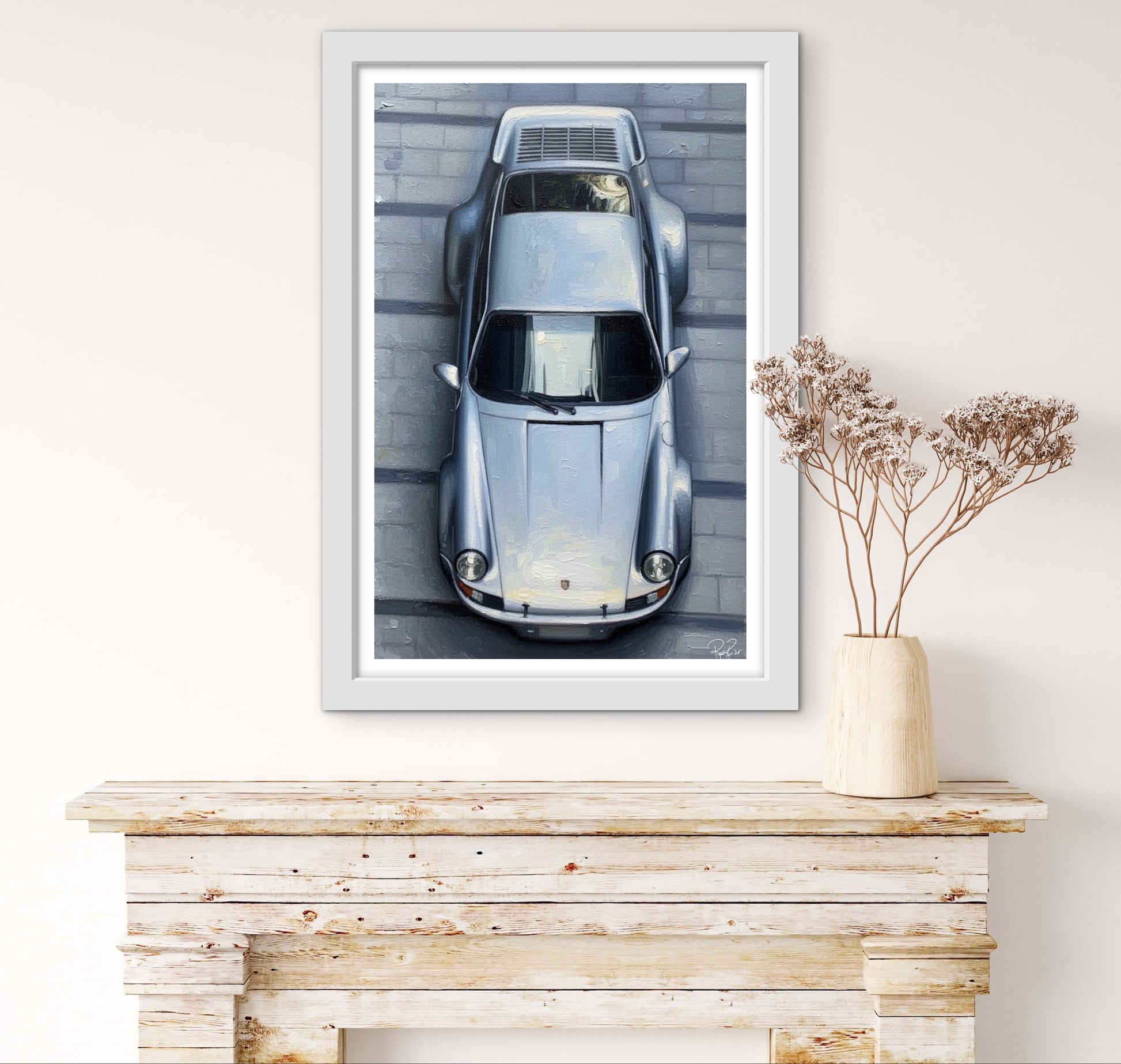 Framed artwork of a vintage car on a wall above a wooden console table.