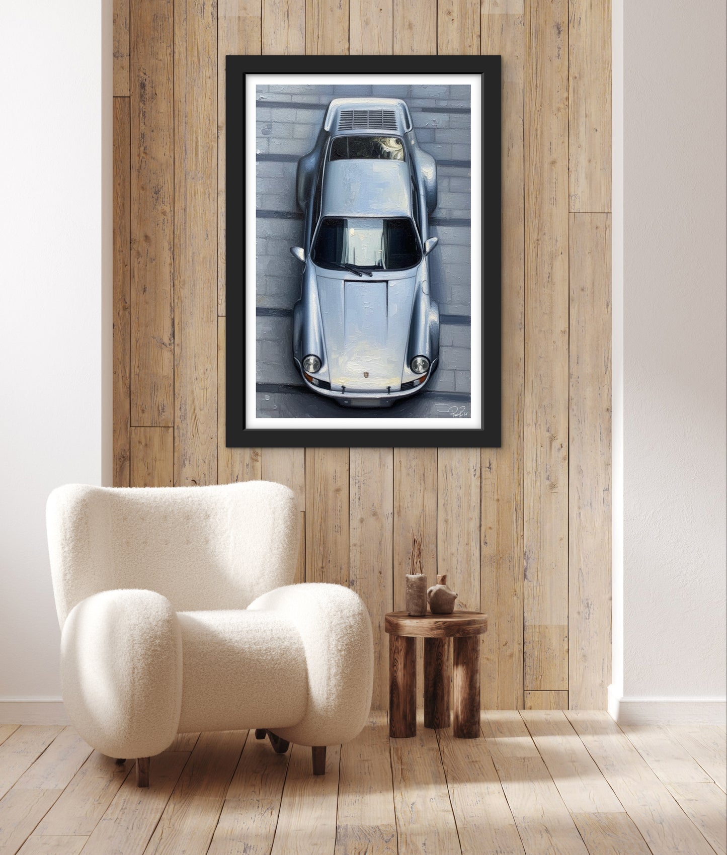 Framed artwork of a car on a wooden wall above a white armchair.