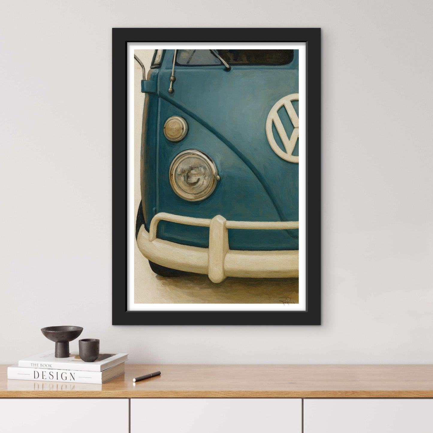 Framed artwork of a vintage blue Volkswagen van on a wall above a wooden shelf.