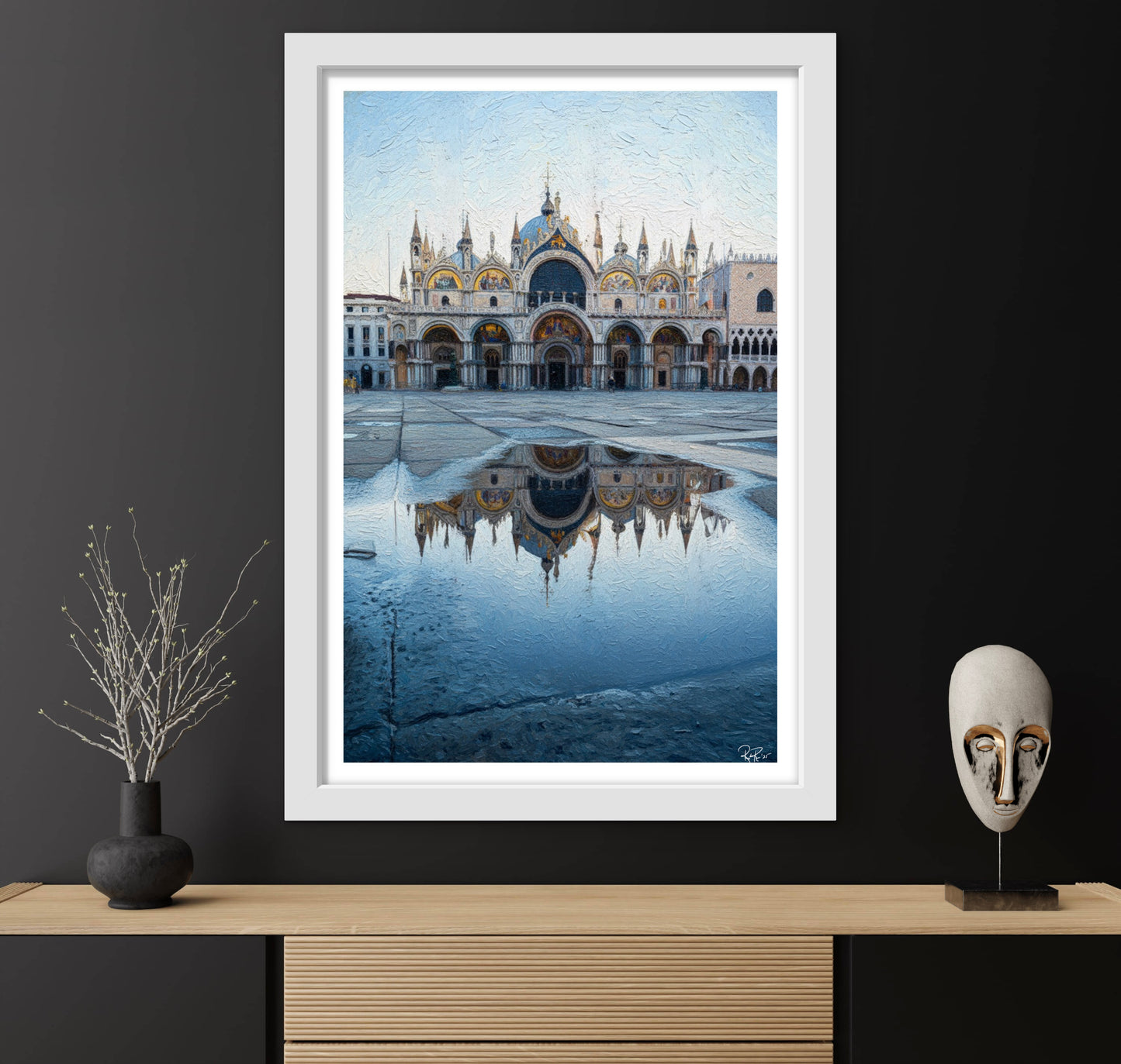 Framed artwork of a cityscape with a large building reflection in water on a dark wall.