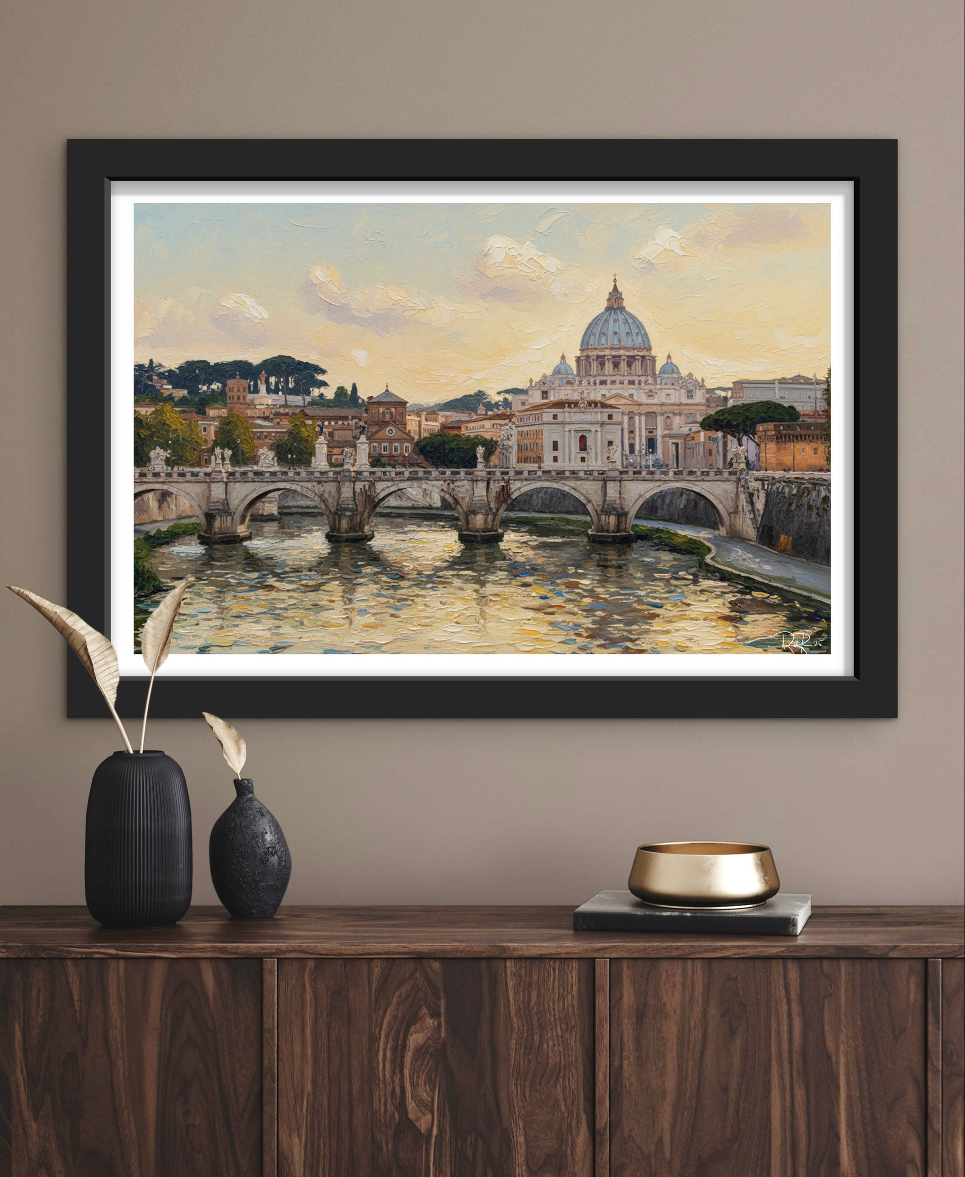 Framed artwork of a cityscape with a bridge over water, displayed on a wall above a wooden cabinet.