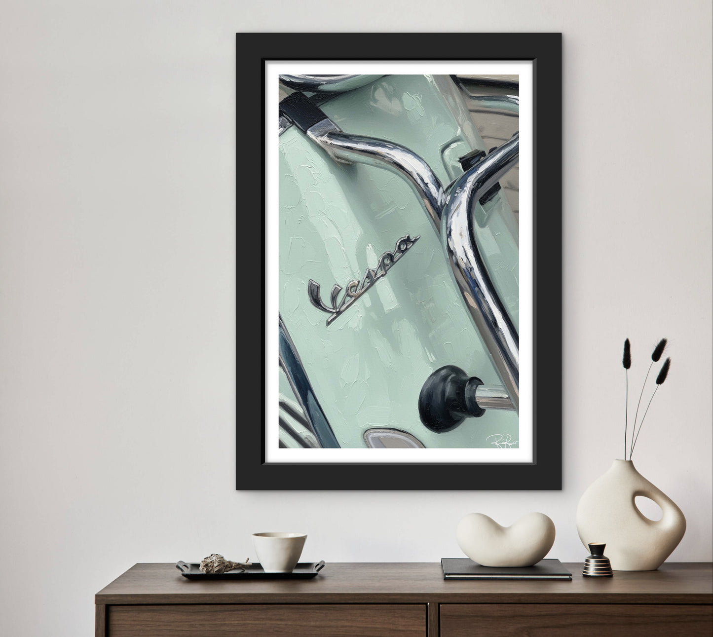Framed artwork of a Vespa logo on a light green background, displayed on a wall above a wooden console table.