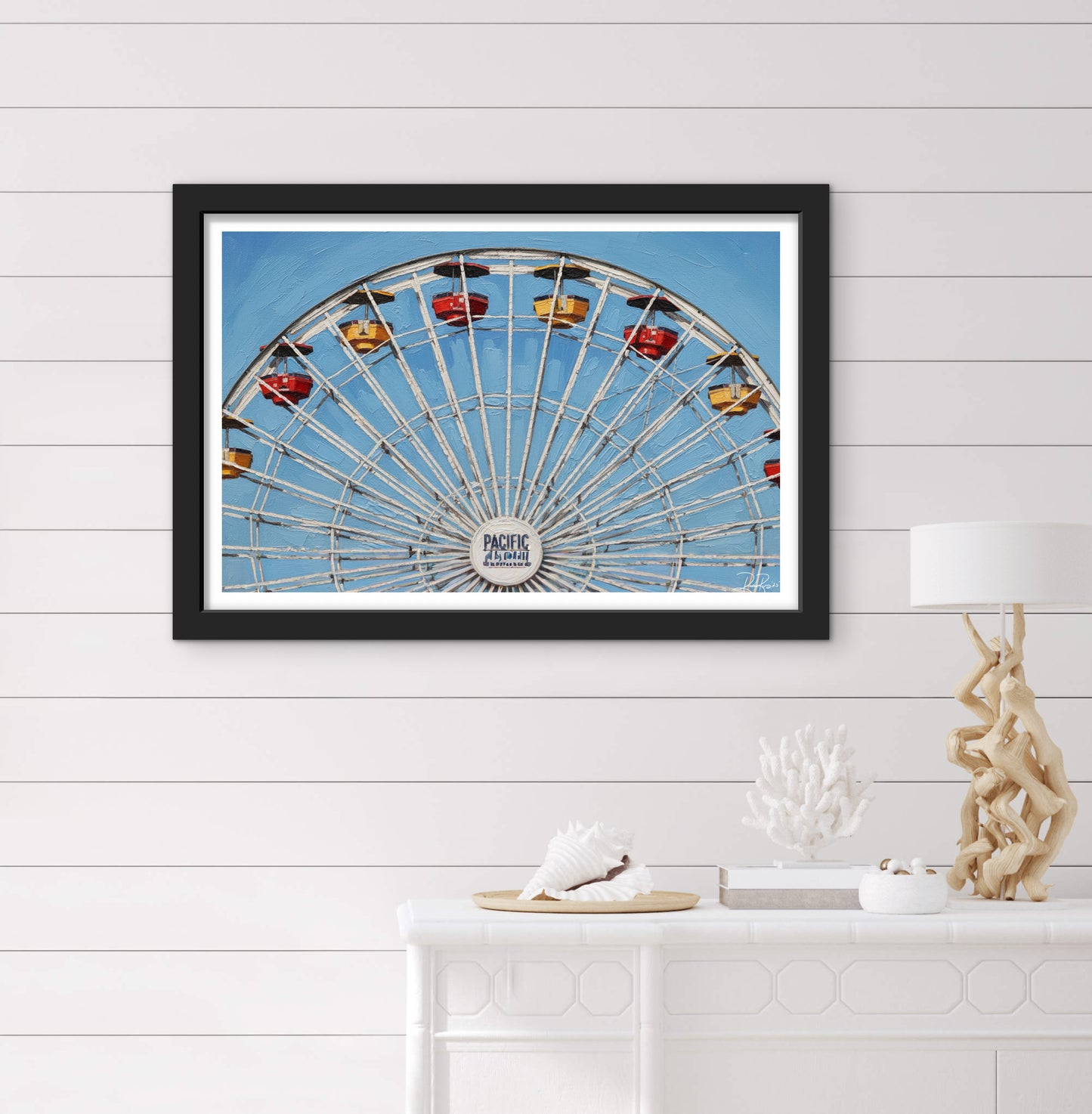 Framed photograph of a Ferris wheel against a blue sky on a white wall.