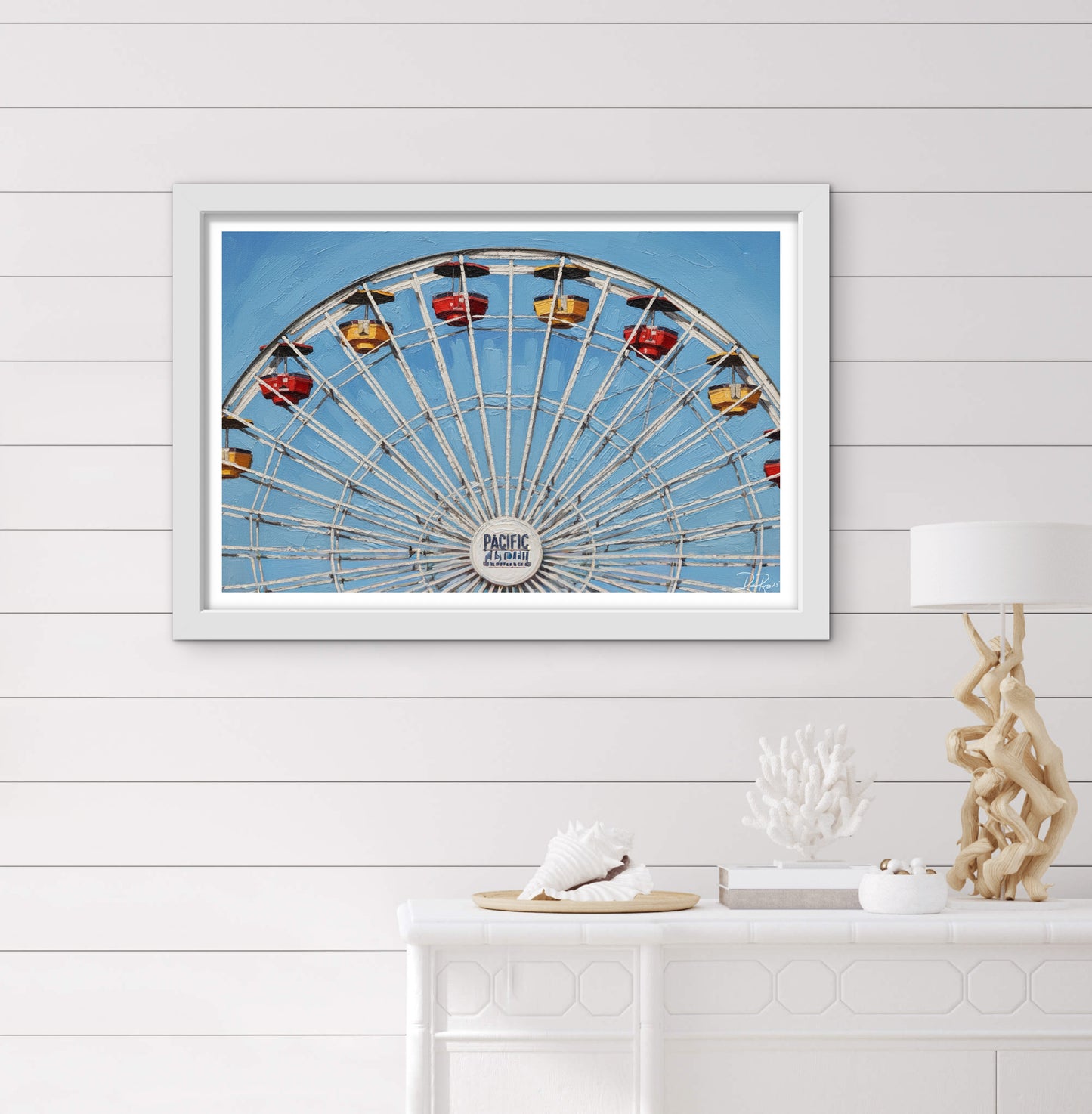 Framed picture of a Ferris wheel on a wall with decorative items below.